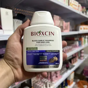 بطری شامپو سیر سیاه بیوکسین ساخت ترکیه در دست